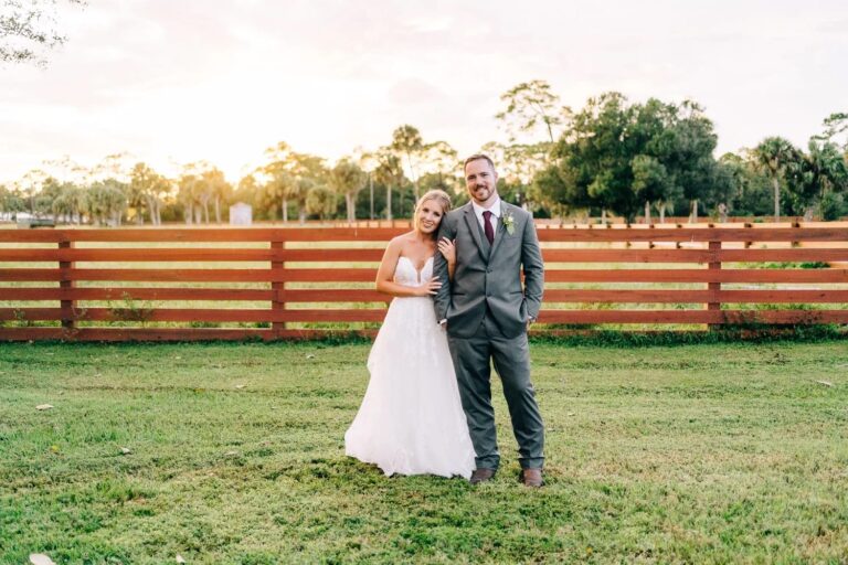 Bride and groom standing in front of ranch wedding venue near palm beach taking photo during the golden hour