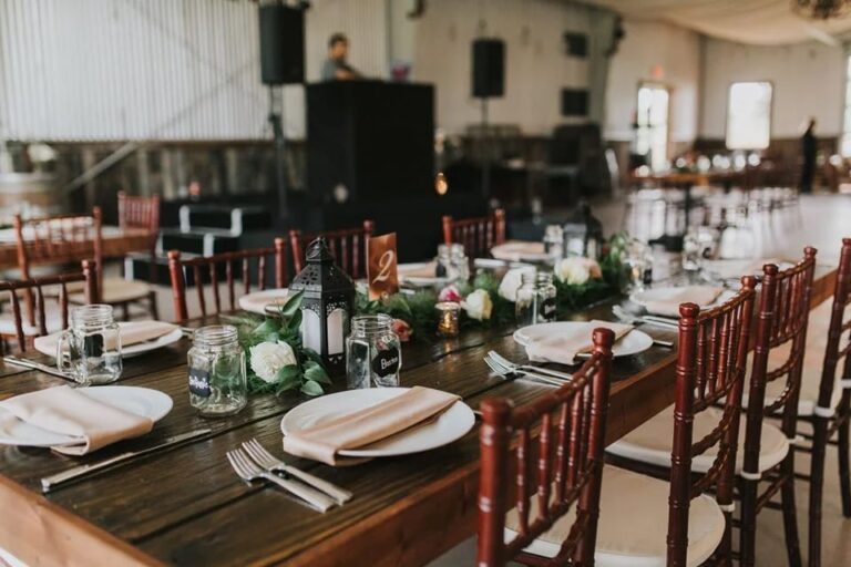 Elegant wedding reception table setup with wooden tables, elegant place settings, and floral greenery decor at a venue near Palm Beach, Florida.