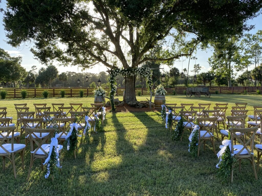 Palm Beach wedding venue outdoor wedding ceremony setup under a large tree adorned with floral decorations at a venue near Palm Beach, Florida.