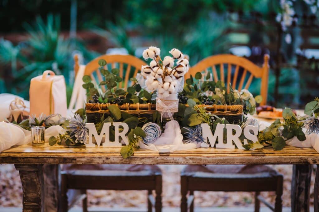 Elegant wedding table setup at Rockin H Ranch near Palm Beach, featuring rustic 'Mr.' and 'Mrs.' decorations, cotton centerpiece, lush greenery, and a charming outdoor backdrop. Perfect for couples seeking a romantic and picturesque venue in South Florida.