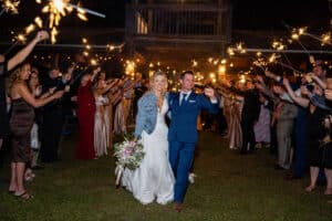 Newlyweds celebrating a sparkler send-off at their South Florida ranch wedding, with the bride in a denim jacket and the groom in a navy suit.